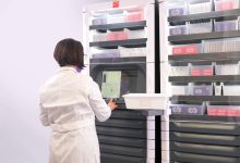Person using an automated vertical storage system with organized shelves