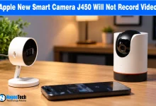 Two white smart home security cameras and a smartphone resting on a wooden tabletop.
