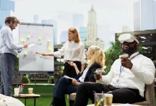 Business team collaborating in an outdoor workspace while a colleague wears a VR headset and holds controllers.