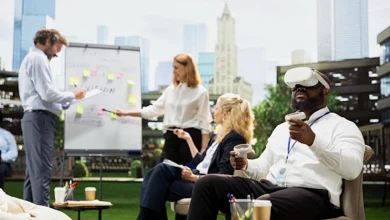 Business team collaborating in an outdoor workspace while a colleague wears a VR headset and holds controllers.